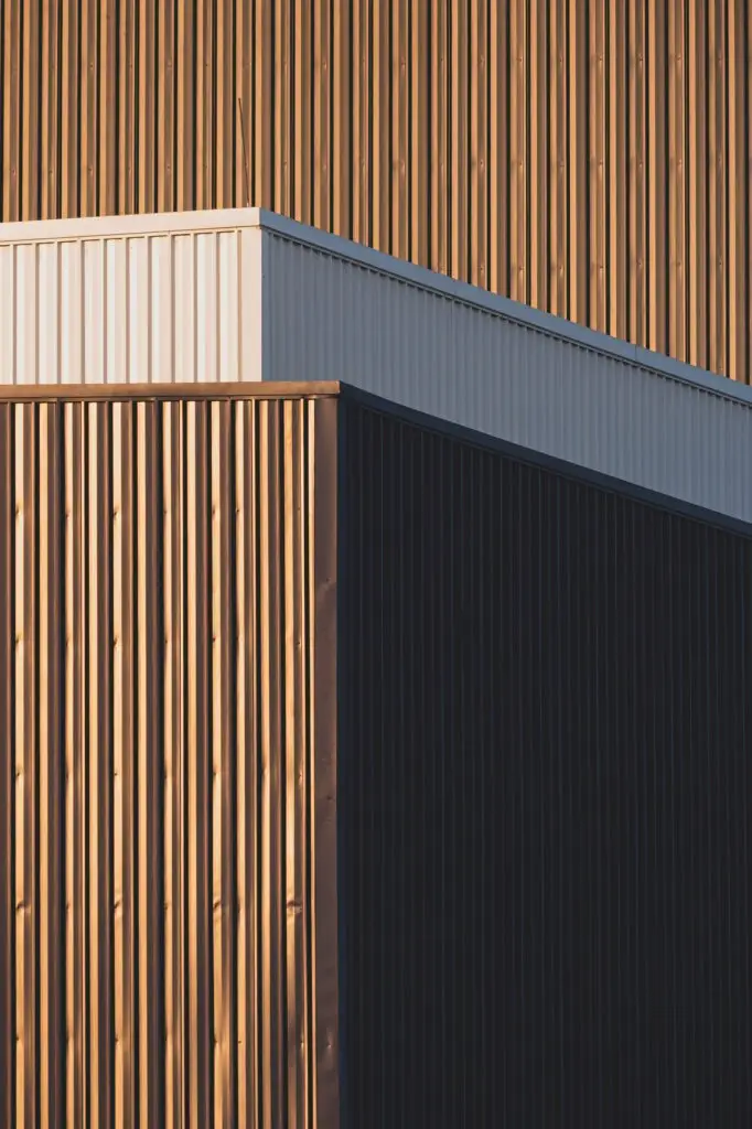 Evening sunlight and shadow on surface of gray and white corrugated metal factory building