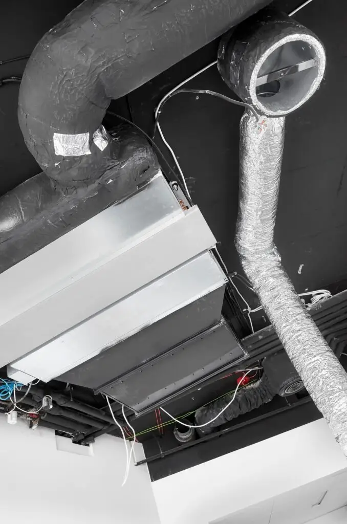 Ventilation system with pipe in silver insulation material in suspended ceiling during renovation.